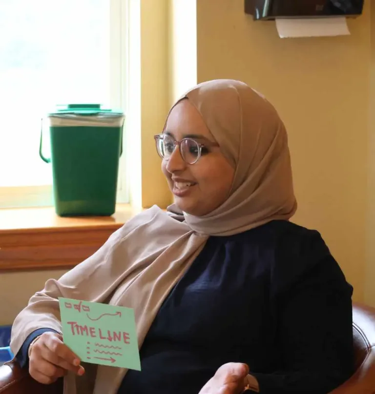A woman holds a card conveying a message in a community setting.