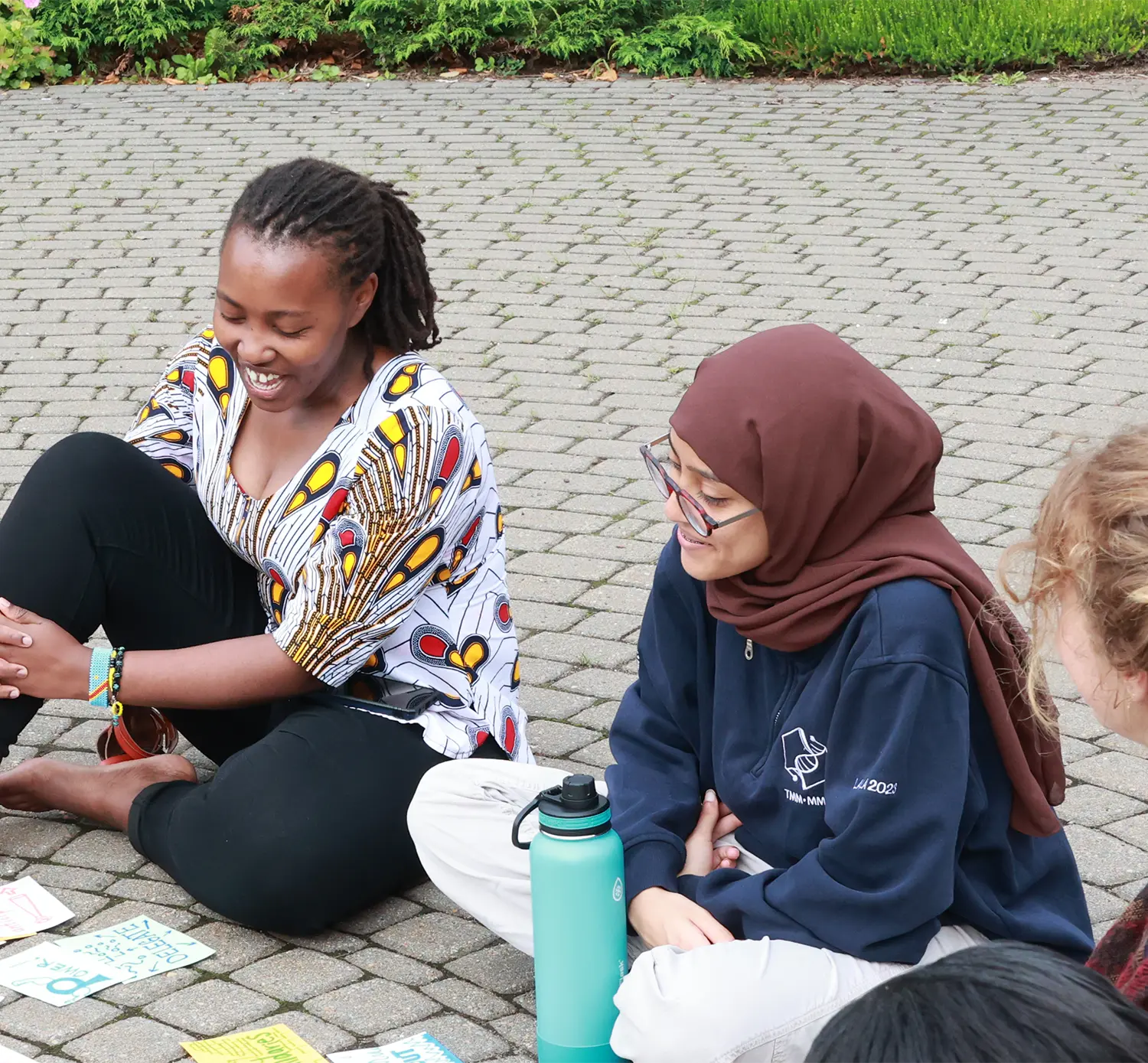 A group of young women sitting on the ground, engaged in conversation